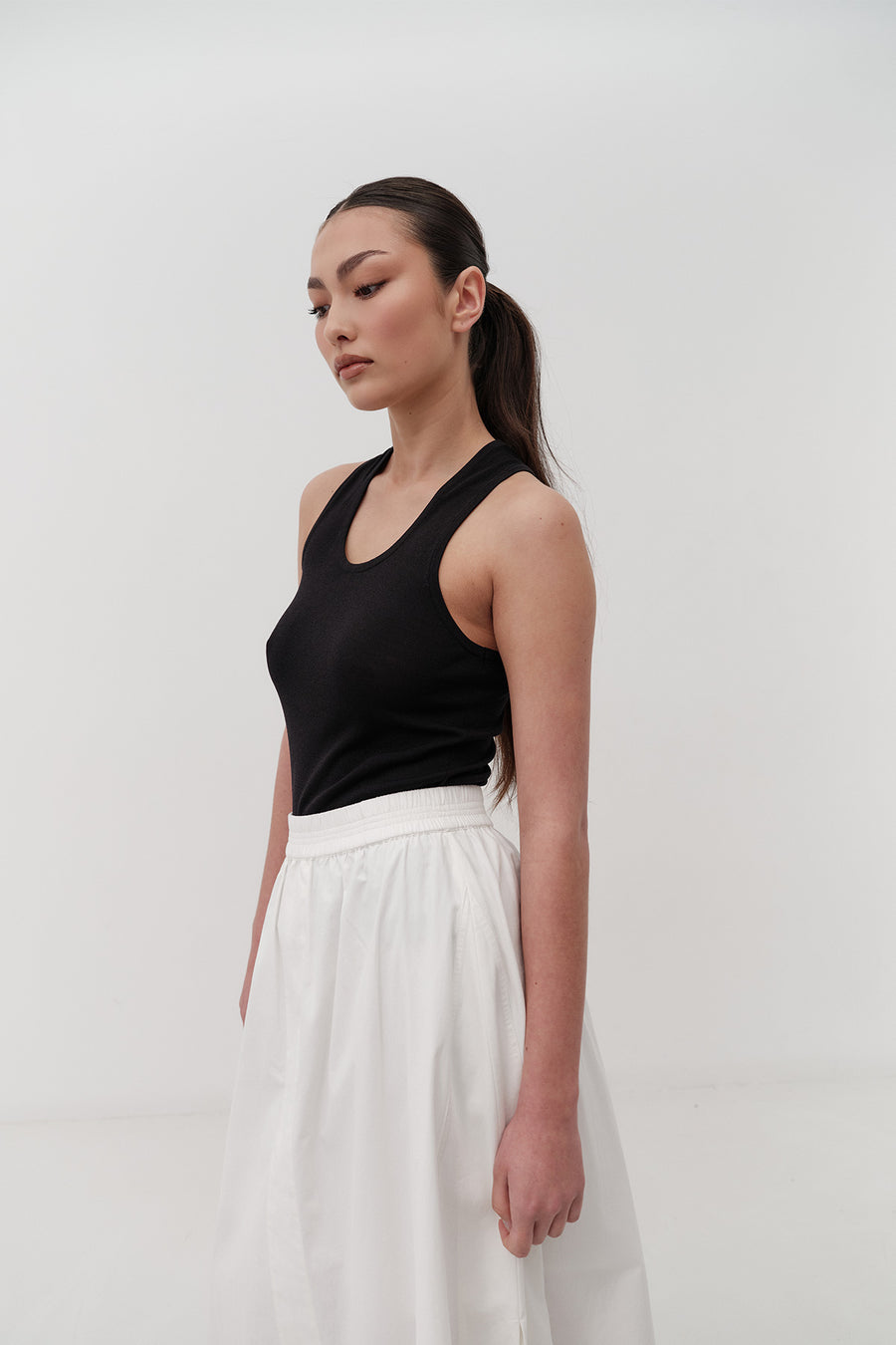 Woman wearing a black tank top and white skirt